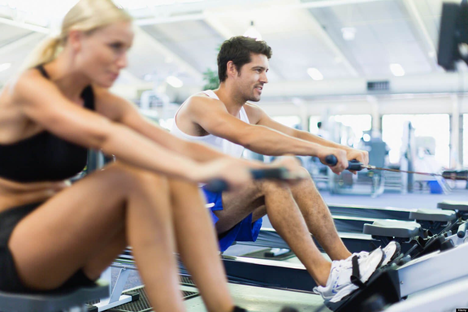 Couple using rowing machines in gym